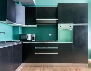 a kitchen with black cabinets and green walls at Milan Emerald Home ''Wifi & Self Check-in'' in Milan