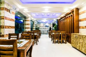 Hotel Pearl - Mahipalpur Delhi Airport في نيودلهي: غرفة طعام مع طاولات وكراسي خشبية