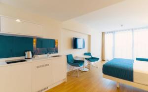 Batumi Next Sea Aparthotel في باتومي: غرفة نوم بسرير ومطبخ وطاولة