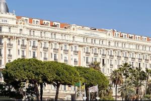 duży biały budynek z drzewami przed nim w obiekcie 2 pièces 2 terrasses 100 m Croisette très clair. w Cannes