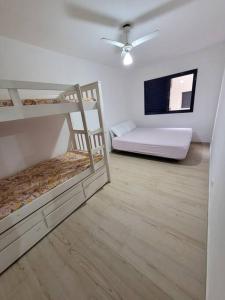 a room with two bunk beds and a tv at Apto inteligente com Alexa, Wi-fi e Smart TV. in Praia Grande