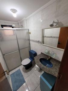 a bathroom with a sink and a toilet and a mirror at Apto inteligente com Alexa, Wi-fi e Smart TV. in Praia Grande