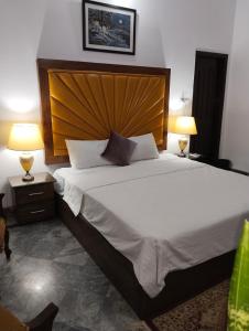 um quarto com uma cama grande e uma cabeceira em madeira em Homewood Suites Family Guest House & Apartments em Lahore