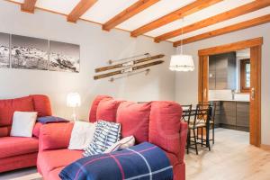 a living room with two red couches and a kitchen at Riu Nere by SeaMount Rentals in Vielha