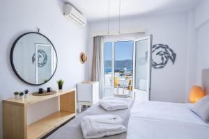 a white bedroom with a bed and a mirror at Argo Hotel in Amoopi