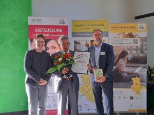 a group of three people holding a award at Pension an der Stadtmauer Apartments in Wernigerode