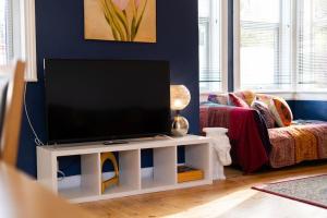 a living room with a flat screen tv on a white stand at Blue Sky Lodge in Overstrand