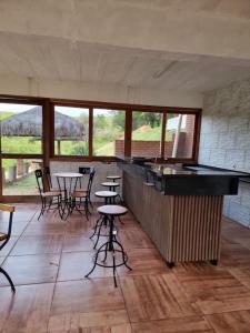 a bar with tables and chairs in a room with windows at Pousada Haras Fazenda Jamaica in Mairinque