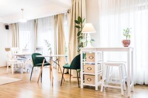 een woonkamer met witte tafels en groene stoelen bij Villa V in Braşov