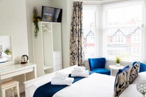 um quarto com 2 camas e uma cadeira azul em Kingsway Guesthouse - A selection of Single, Double and Family Rooms in a Central Location em Scarborough