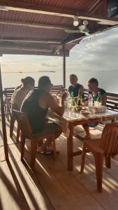 un groupe de personnes assises autour d'une table en bois dans l'établissement Yohana Cottage, à Tual