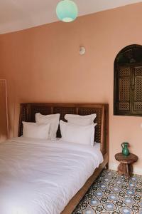 um quarto com uma cama grande e almofadas brancas em Riad Maison 24 em Marrakech