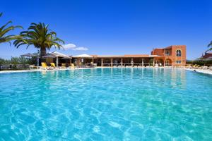 a large swimming pool with a resort in the background at Colina Village in Carvoeiro