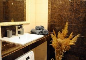 ein Badezimmer mit einem Waschbecken, einem Spiegel und Handtüchern in der Unterkunft BoHo Apartment near Center! in Chişinău