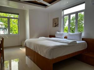 Schlafzimmer mit einem großen Bett mit weißer Bettwäsche und Fenstern in der Unterkunft PINE LODGE MALDIVES in Hulhumale