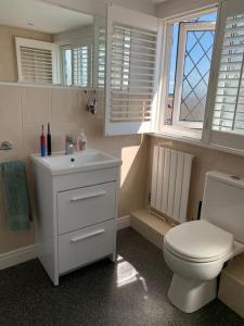a bathroom with a toilet and a sink and a window at 3-Bedroom Family Home. Just 5 Mins From The Beach! in Kent