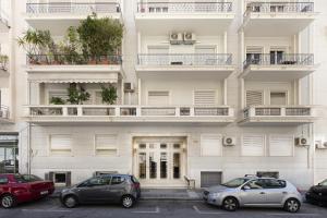 un edificio blanco con coches estacionados frente a él en Kolonaki 2 Bdr apartment, en Atenas