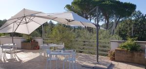 un patio con sombrilla blanca, mesas y sillas en B&B casaMagliana en Itri
