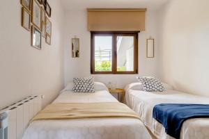 two beds in a room with a window at Casa de Las Flores - Apartamento con jardín privado frente a la Playa de Comillas in Comillas