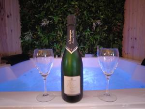 una botella de vino y dos copas de vino en una mesa en HOTEL DU BERRY - Loveroom avec Sauna, Hammam, Jacuzzi privatifs, en Reuilly