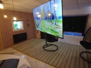 a large screen television in a living room with a chair at HOTEL DU BERRY - Loveroom avec Sauna, Hammam, Jacuzzi privatifs in Reuilly