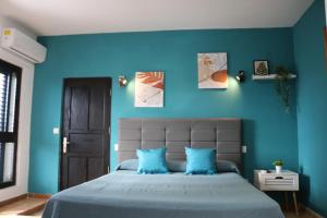 1 dormitorio con paredes azules y 1 cama con almohadas azules en Apartamentos La Carmen, en Arrecife