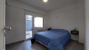 Un dormitorio con una cama azul y una ventana en Departamento con vista al lago y cerros en San Carlos de Bariloche
