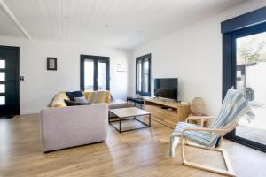 a living room with a couch and a tv at CAP O SUD grande maison avec Piscine à St Martin de Ré in Saint-Martin-de-Ré