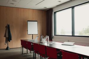 a conference room with a long table and red chairs at Holiday Club Saimaan Rauha in Imatra