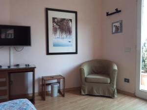uma sala de estar com uma cadeira e uma televisão em Balcone Fiorito em Menaggio