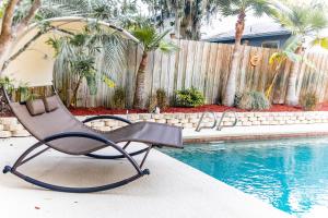 une chaise assise à côté de la piscine dans l'établissement Pool & Hot Tub Home w Game Room! 1 Mile to Beach!, à Jacksonville Beach
