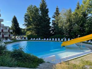 a swimming pool with chairs and a yellow slide at Ferienapartment Auszeit wie dahoam Am Predigtstuhl in Sankt Englmar
