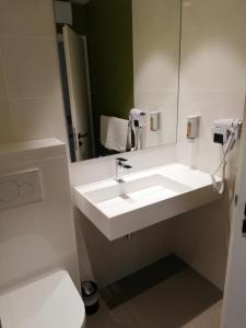 a bathroom with a white sink and a mirror at Le Kléber Hôtel in Strasbourg