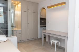 une cuisine avec des placards blancs, une table et un tabouret dans l'établissement Villa Livana Naxos, à Kastraki Naxou