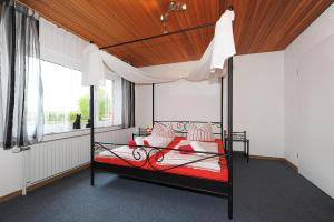 um quarto com uma cama de dossel com almofadas vermelhas e brancas em Haus Sonnenperle em Utarp
