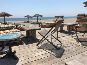 - une terrasse en bois avec des tables et des chaises sur la plage dans l'établissement Appartement Port Leucate, 3 pièces, 6 personnes - FR-1-81-83, à Port-Leucate