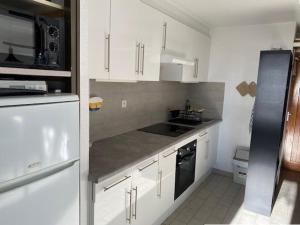 a kitchen with white cabinets and a black refrigerator at Studio Cabine à Le Barcarès, 4 couchages, terrasse, parking, piscine et activités sportives - FR-1-195-23 in Le Barcarès