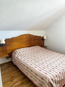 Schlafzimmer mit einem Bett mit einem Kopfteil aus Holz in der Unterkunft VVF Résidence Albiez-Montrond Maurienne in Albiez-Montrond