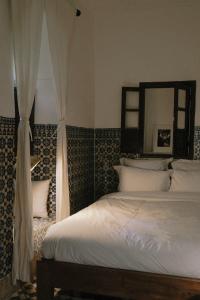 um quarto com uma cama branca e um espelho em Riad Maison 24 em Marrakech
