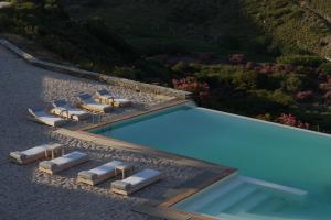 an overhead view of a swimming pool with lounge chairs and a swimming pool at Aegea Blue Cycladic Resort in Zorgos 
