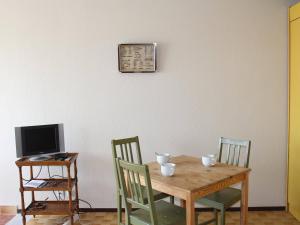 a wooden table with chairs and a computer on a desk at Appartement Gruissan, 2 pièces, 4 personnes - FR-1-229-292 in Gruissan