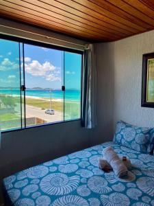 Un dormitorio con una cama con vista al mar. en Pousada Casa do Telhado Verde, en Cabo Frío
