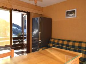 a kitchen with a stainless steel refrigerator and a couch at Appartement Le Grand-Bornand, 1 pièce, 4 personnes - FR-1-241-98 in Le Grand-Bornand