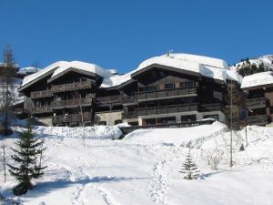 ein großes, schneebedecktes Gebäude mit Bäumen davor in der Unterkunft Valmorel: Appartement 3 Pièces, 6 Pers., WiFi, Balcon, Casier à Skis - FR-1-291-705 in Valmorel