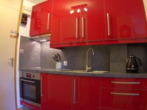een keuken met rode kasten en een wastafel bij Appartement Valmorel, 1 pièce, 4 personnes - FR-1-291-702 in Valmorel