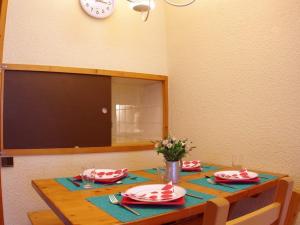 een eettafel met borden en een klok aan de muur bij Appartement Valmorel, 1 pièce, 4 personnes - FR-1-291-757 in Valmorel
