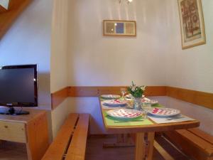 a table with plates and a television in a room at Appartement Valmorel, 3 pièces, 8 personnes - FR-1-291-766 in Valmorel