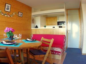 a dining room with a table and a red couch at Studio Valmorel, 2 pièces, 4 personnes - FR-1-291-772 in Valmorel