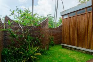 a brick wall with a wooden fence in a yard at The Spice Trail, Ahangama in Ahangama