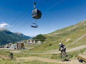 two people riding bikes on a hill with a ski lift at Appartement Orcières Merlette, 1 pièce, 6 personnes - FR-1-262-123 in Forest des Baniols